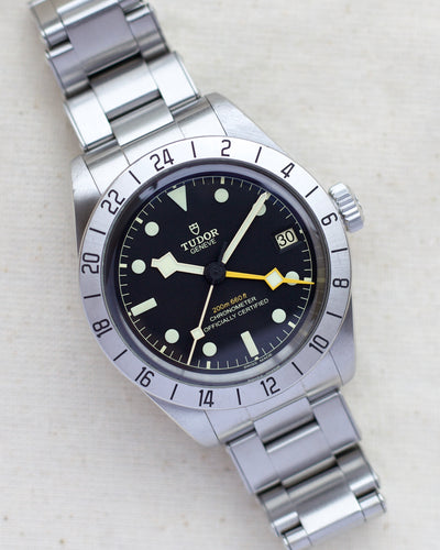Tudor steel watch with black dial and orange hand
