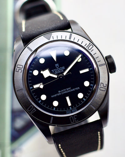 Tudor watch with black dial and leather strap on a white background