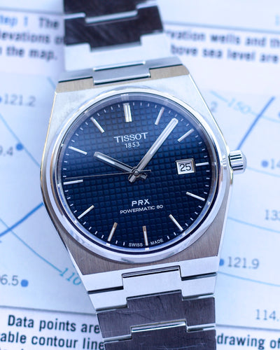 Tissot PRX watch with blue dial on a map background