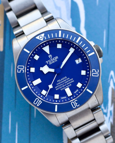 Tudor Pelagos watch with blue dial and silver bracelet on a blue background