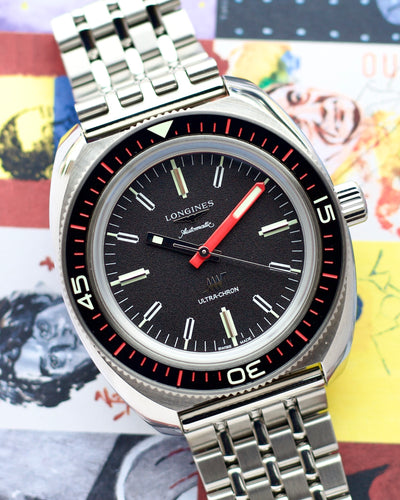 Longines watch with a black dial and red accents on a colorful background
