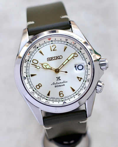 steel wristwatch with creamy dial and green strap