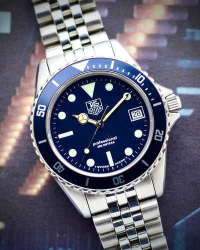 Tag Heuer watch with blue dial and silver metal bracelet on a blurred background