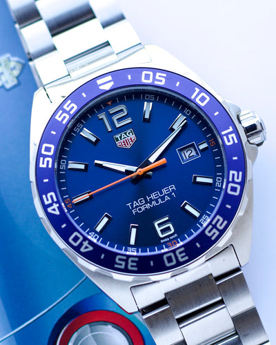Tag Heuer watch with blue dial and silver bracelet on a blue background