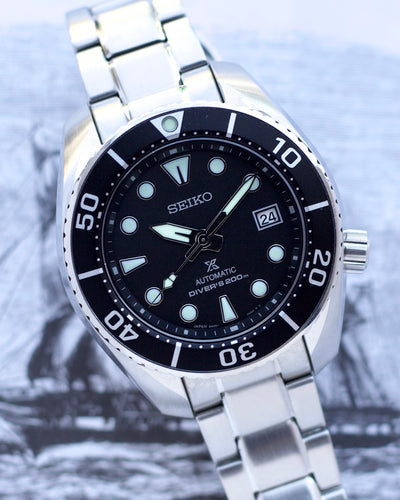 Seiko watch with black dial and silver metal strap on a blurred background
