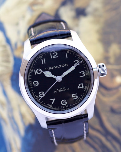 Hamilton watch with black dial and leather strap on a blurred background