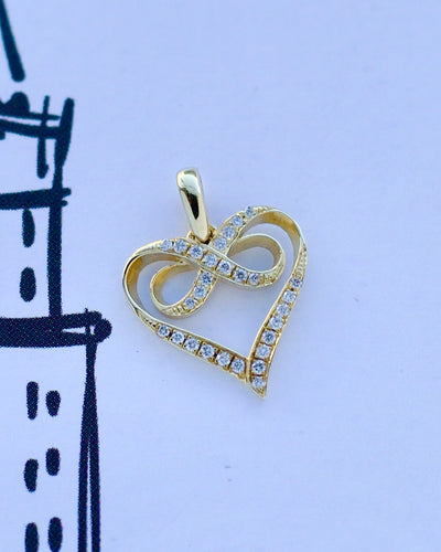 Gold heart-shaped pendant with diamonds on a light purple background