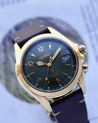 Seiko watch with blue strap and gold casing on a blurred background