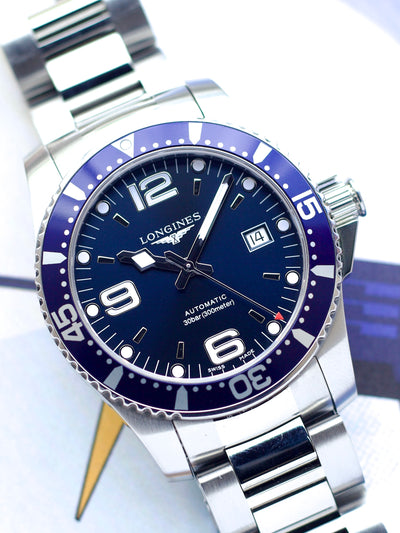 Longines watch with blue dial and silver metal strap on a light background