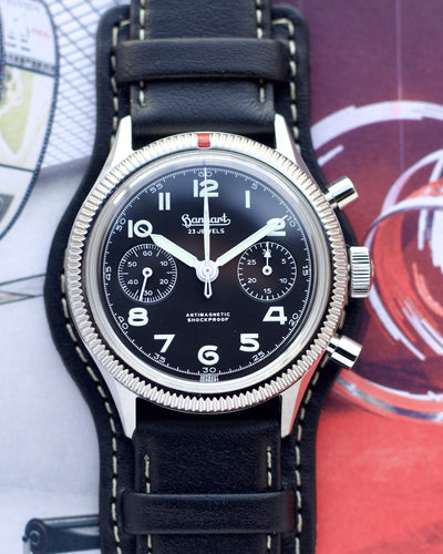 Watch with black leather strap and black dial on a colorful background