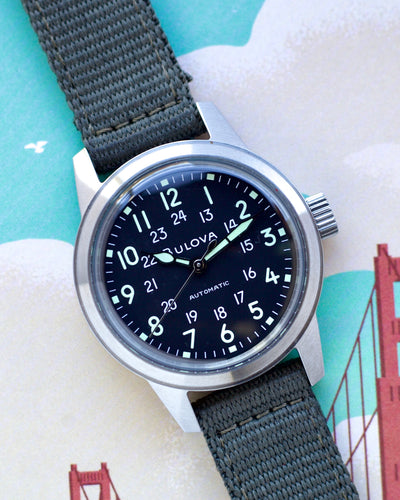 Watch with a dark face and gray strap on a decorative background
