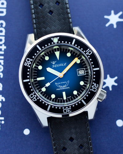 Squale watch with blue dial and black strap on a blue background