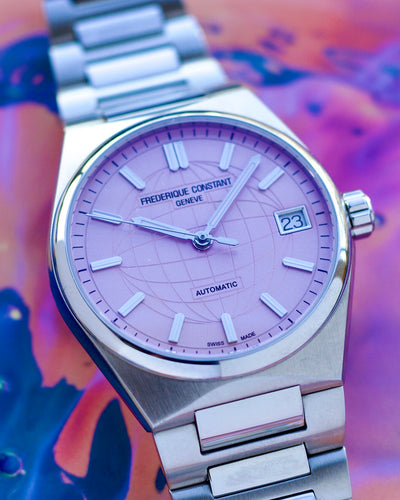 Frederique Constant watch with purple dial and silver metal strap on a colorful background