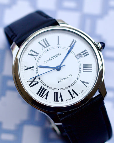Cartier watch with a white face and blue hands on a blue background