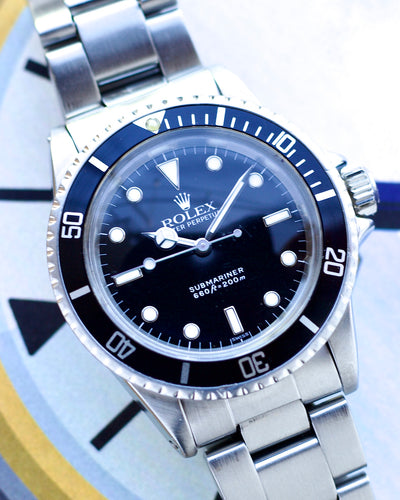 Close-up of a Rolex watch with a blue bezel and black dial.