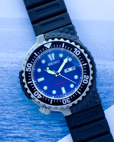 Seiko watch with blue dial and black rubber strap on a blue background