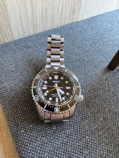 Seiko diver Watch in stainless steel with black face on a gray carpet