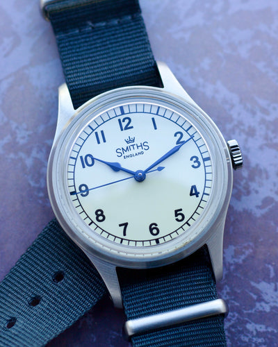 Watch with blue strap and white face on a textured purple background