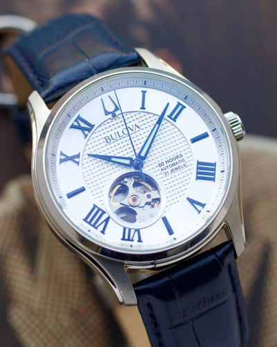 Bulova watch with blue strap and white face featuring Roman numerals.