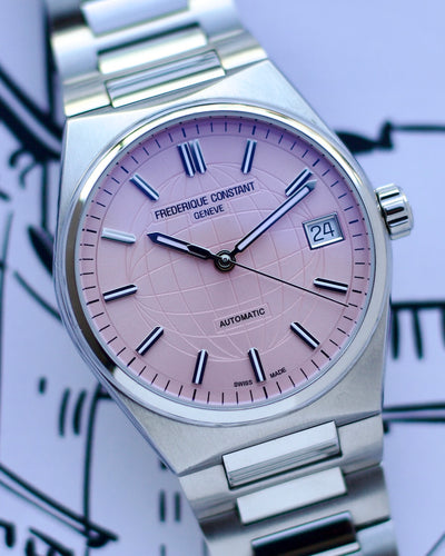 Frederique Constant watch with pink dial and silver case on a blurred background