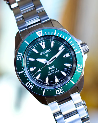 Seiko watch with green dial and silver metal strap on a blurred background
