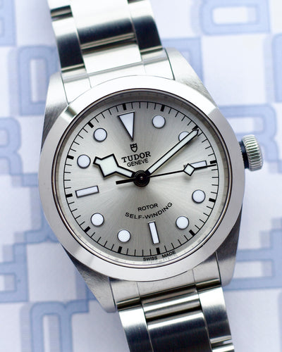 Silver Tudor watch with a detailed face on a light blue geometric patterned background