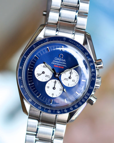 Silver Omega watch with blue face on a blurred background