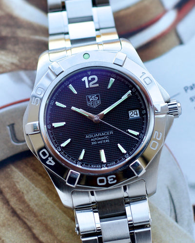 Silver watch with a dark face on a wooden surface