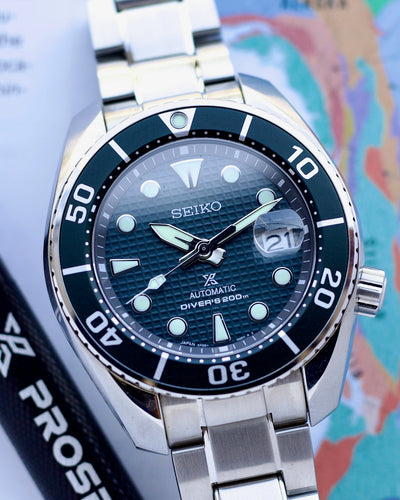 Seiko watch with a blue dial and silver bracelet on a world map background