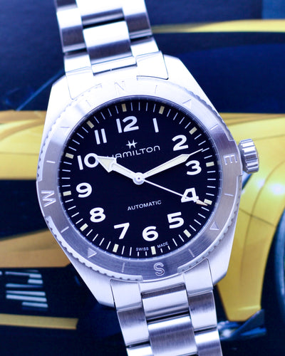 Silver Hamilton watch with black dial on a blurred background