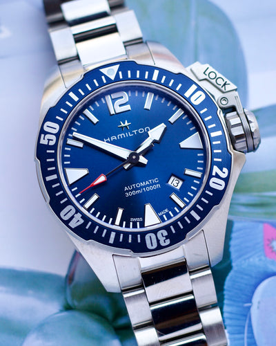 Hamilton watch with blue dial and silver bracelet on a blurred background
