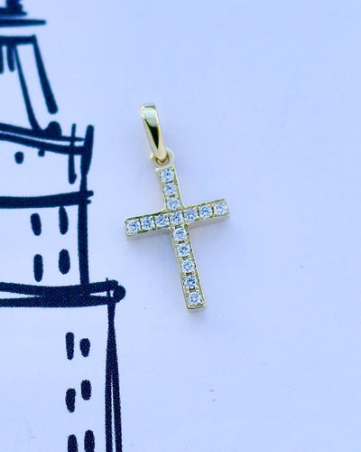 Gold cross pendant with diamonds on a light blue background