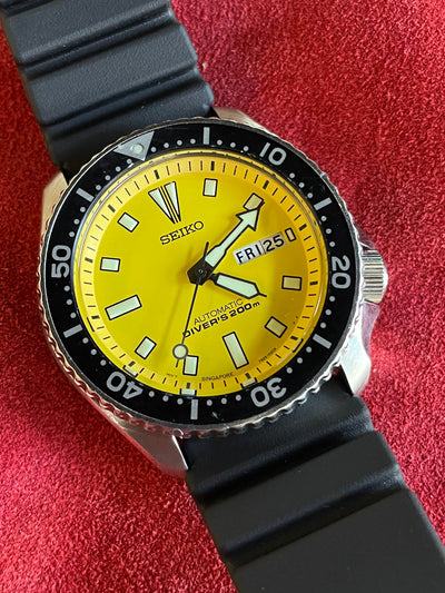 seiko watch on steel with yellow dial and black rubber band