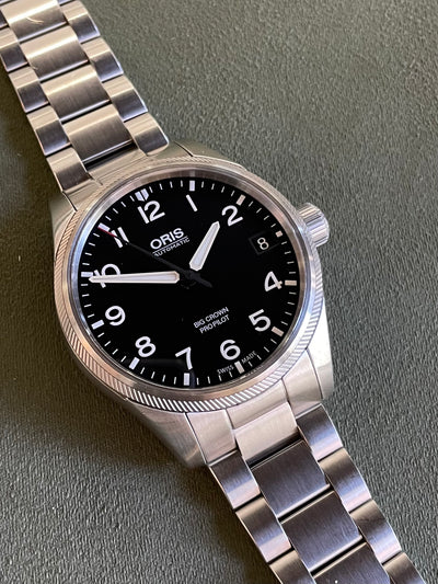 Oris steel watch on black dial and bracelet
