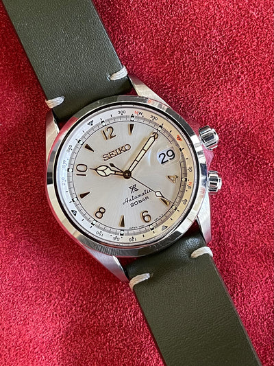steel wristwatch with creamy dial and green strap