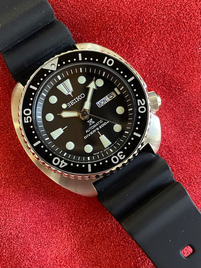 steel watch on black dial and black rubber starp 
