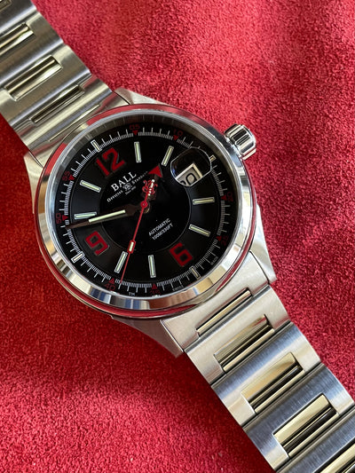 steel wristwatch on black dial with red accent and steel bracelet