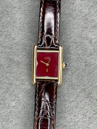 gold tone wristwatch with red dial and brown band