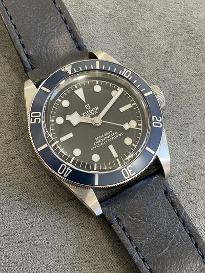 Steel wristwatch on blue leather and black dial
