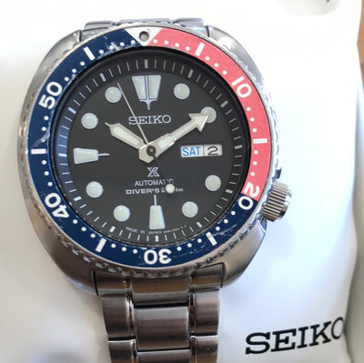 steel wrist watch on black dial and blue and red bezel