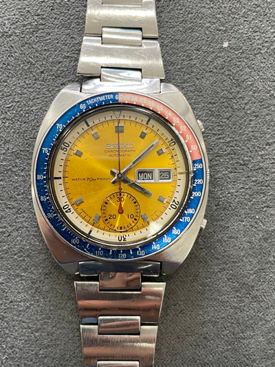 steel wristwatch on orange sunburst dial